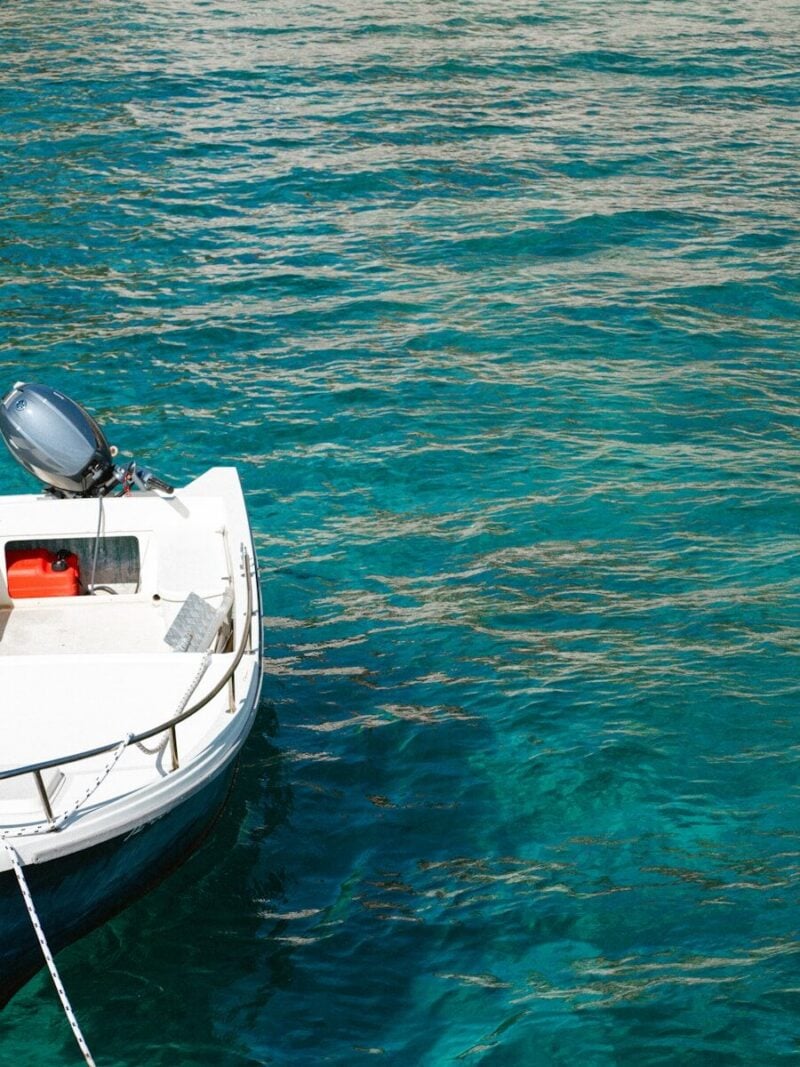 A white boat floats on clear blue water